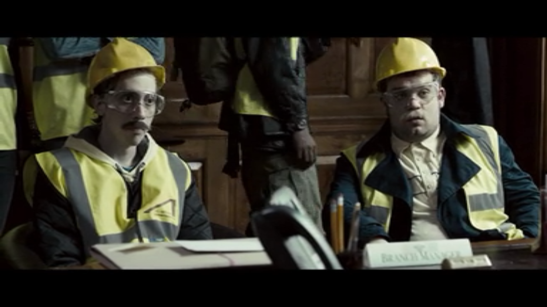 two men in construction crew uniforms wear fake mustaches