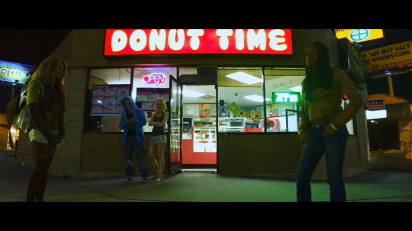 two women stand outside of a shop called Donut Time.