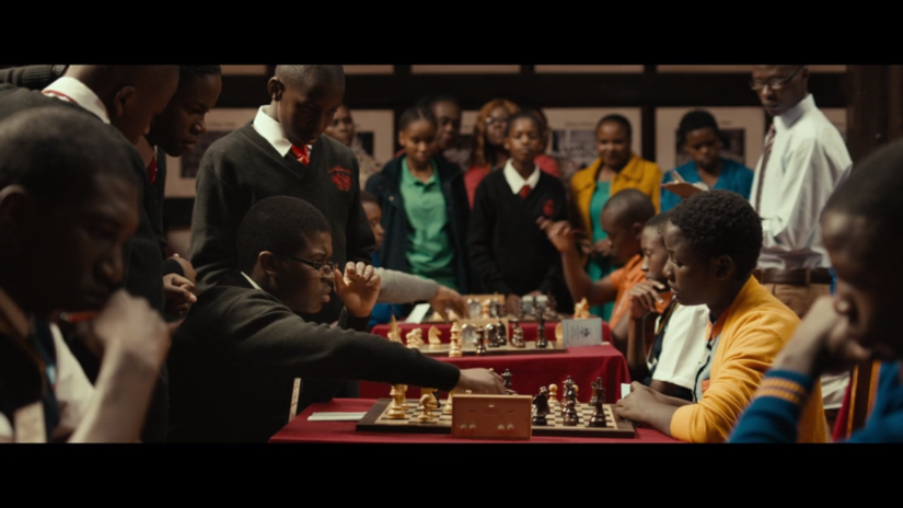 A room is filled with African teens competing in many different chess games.