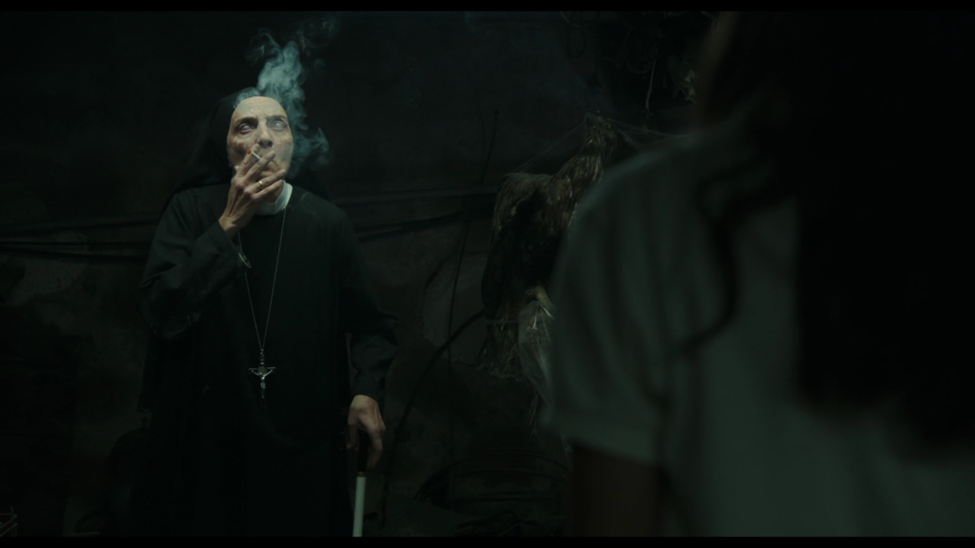 a blind nun smokes a cigarette in a dark basement