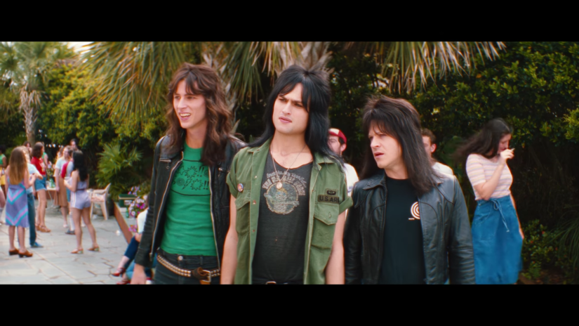 three young men in punk clothing look into the distance among people at an outdoor party