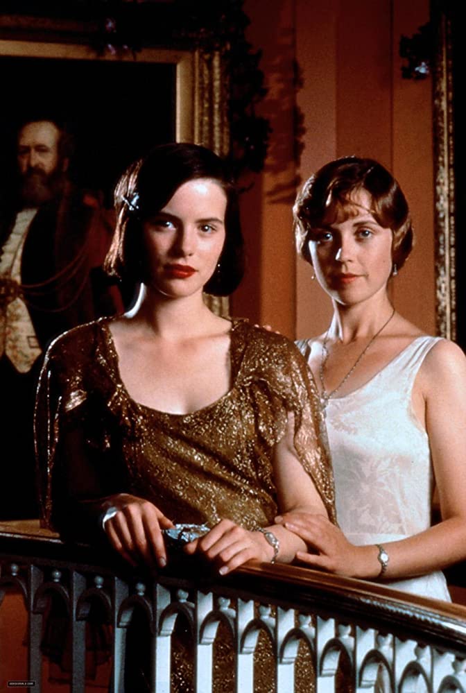 Two woman stand side by side in glamorous dresses, looking directly at the camera.