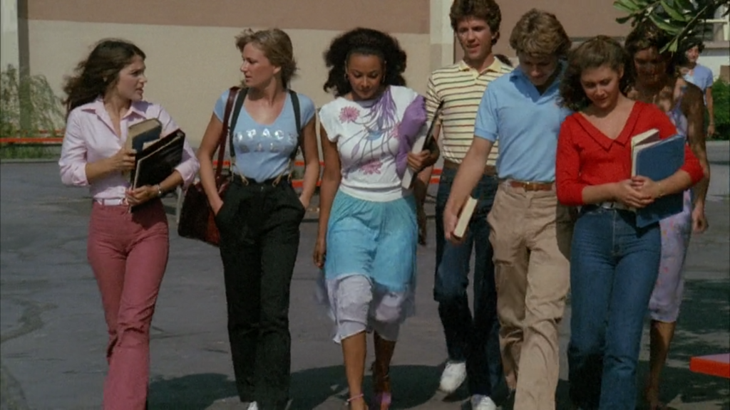 A group of teenagers walk together away from their school building.