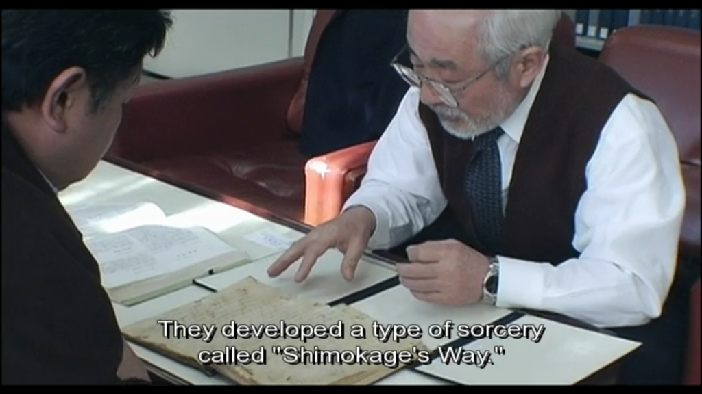 Kobayashi talks to a local historian, an older man with white hair and glasses. They are looking at old documents, and the historian says "They developed a type of sorcery called 'Shimokage's Way.'"